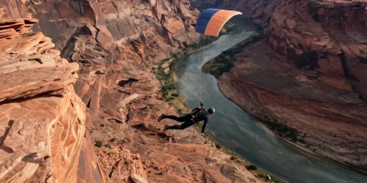A breathtaking aerial view of a person base jumping from a cliff in Moab, Utah, with red rock formations and a river below, dramatic lighting, hyper-realistic style, wide-angle shot.