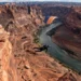 A breathtaking aerial view of a person base jumping from a cliff in Moab, Utah, with red rock formations and a river below, dramatic lighting, hyper-realistic style, wide-angle shot.