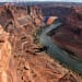 A breathtaking aerial view of a person base jumping from a cliff in Moab, Utah, with red rock formations and a river below, dramatic lighting, hyper-realistic style, wide-angle shot.